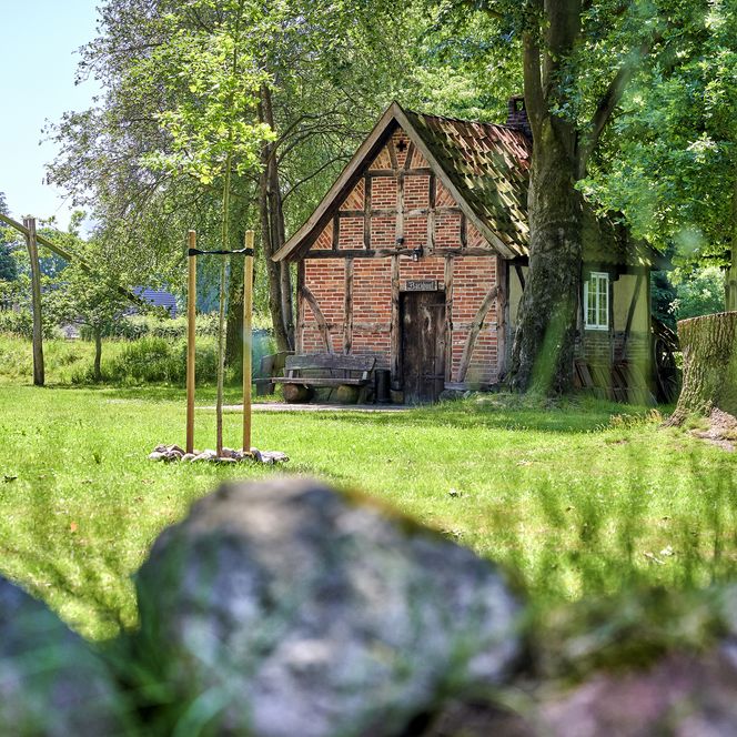 Altes Fachwerkhaus im Fresldorfer Brink. Vor dem Haus steht eine alte Bank. Rechts davon ist ein Baumstumpf zu sehen.